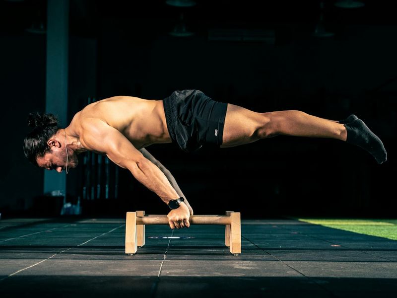 Person performing a precise bodyweight exercise on a dark mat, showcasing control and balance.