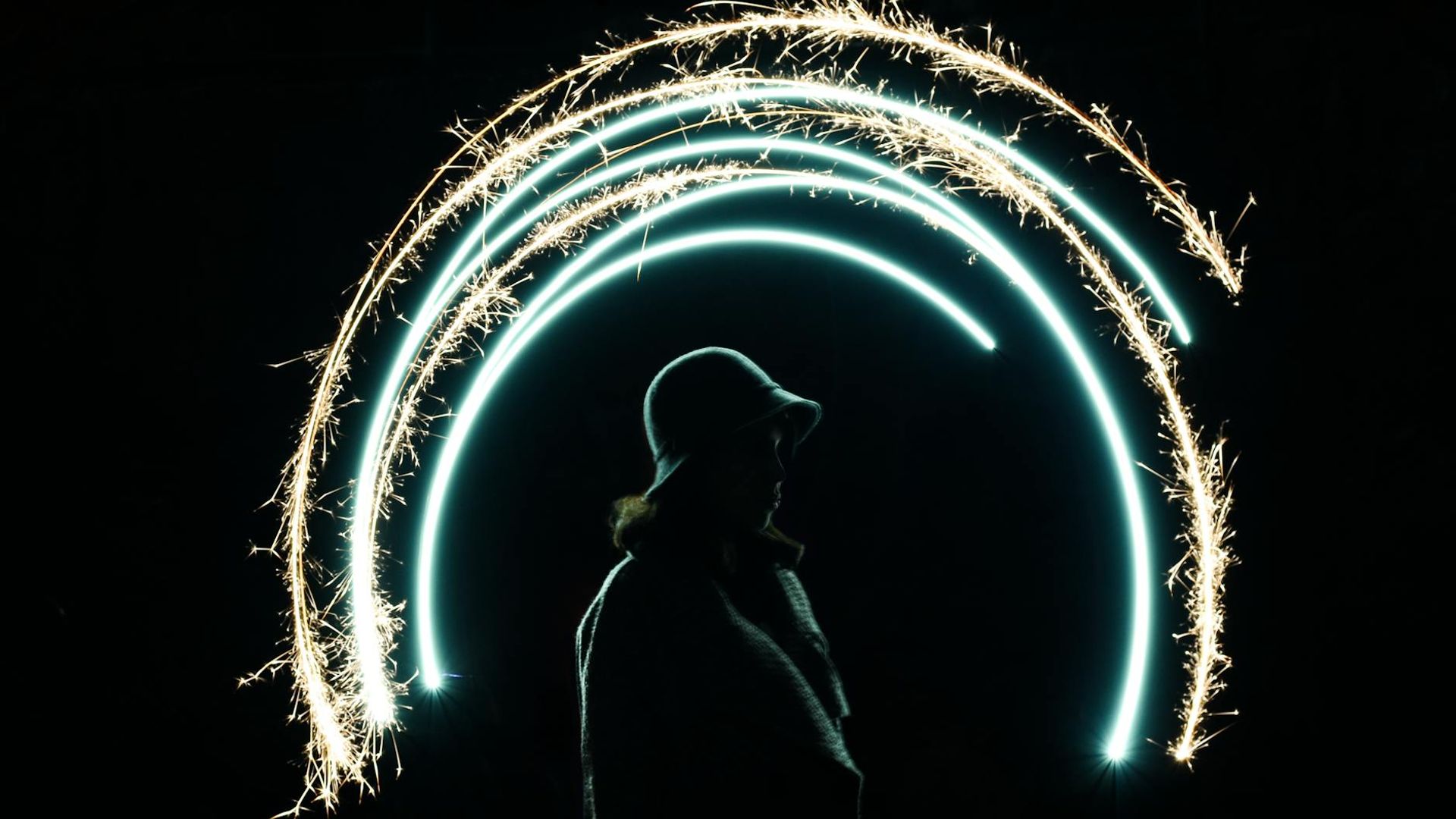 Silhouette of a person in a dynamic stretching pose against a dark background with neon green light trails.